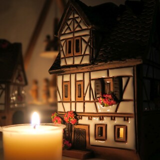 Wei�es Fackwerk Keramik Lichthaus vor Kerze